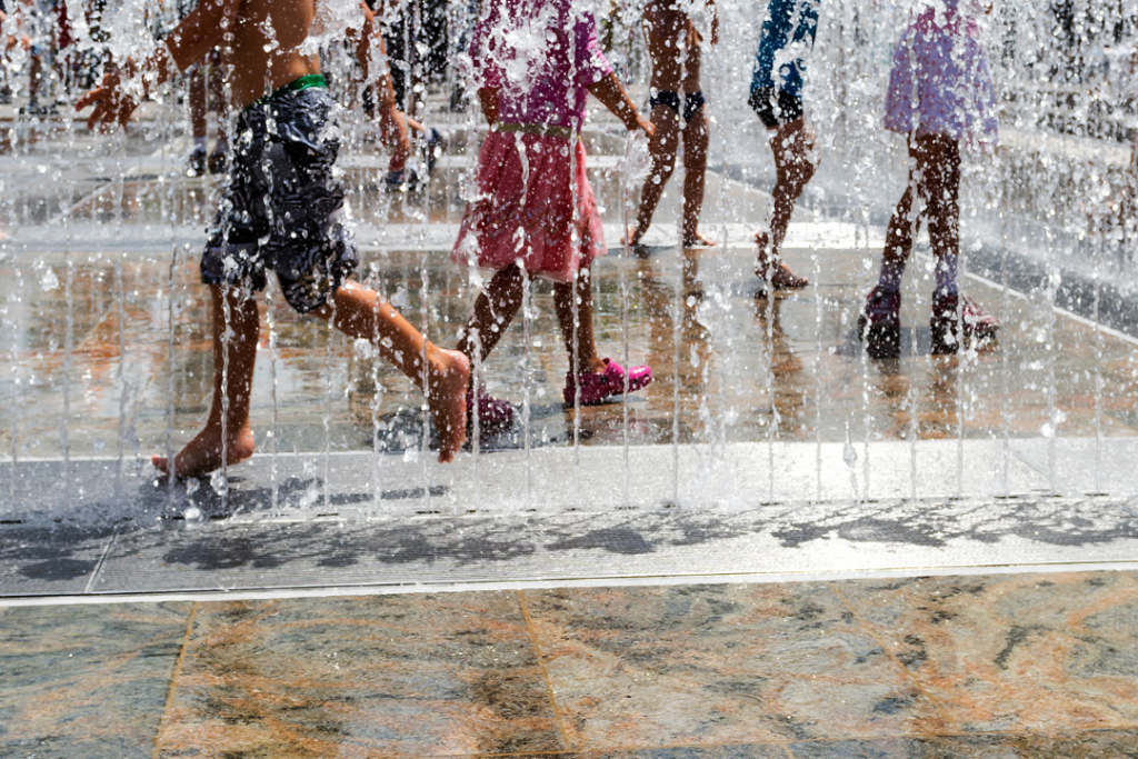 children running through water fountain