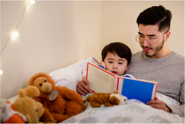 a boy and his father reading a book before bed